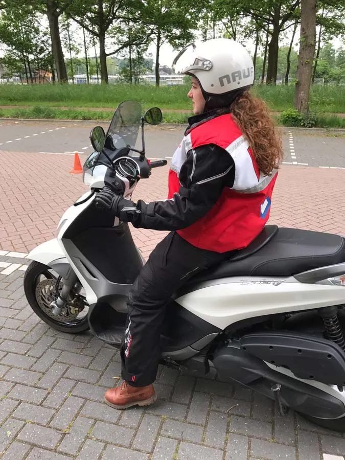 Leerling op een scooter van Rijschool Amsterdam oefent tussen de pionnen op een oefenterrein.